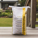 Ochre Living jointing adhesive bag standing on a timber deck in a residential backyard, showing construction adhesive used for outdoor fireplace and masonry installation