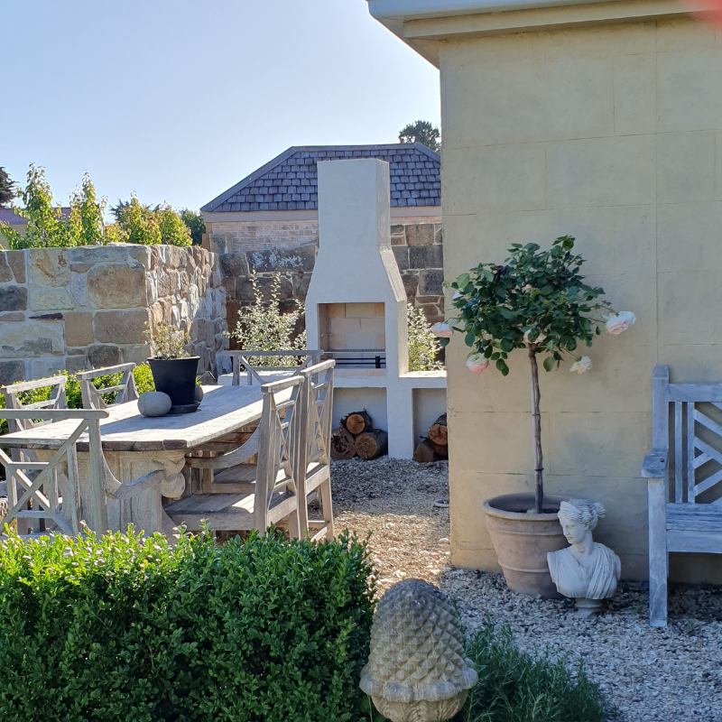 Front studio image of the Ochre Living Ossa Complete Fireplace Kit showing the main rendered outdoor fireplace with chimney and lower log storage opening on a plain background.