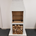Angled front-right studio image of the Ochre Living Ossa Complete Fireplace Kit with three lower storage openings and a rendered chimney fireplace design on a plain background.