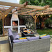 Outdoor entertaining area with a pergola and lighting, featuring the Ochre Living Ossa Complete Fireplace Kit burning firewood, with built-in log storage and seating, demonstrating outdoor fireplace ideas in Australia for backyard dining and entertaining.