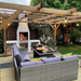 Outdoor entertaining area with a pergola and lighting, featuring the Ochre Living Ossa Complete Fireplace Kit burning firewood, with built-in log storage and seating, demonstrating outdoor fireplace ideas in Australia for backyard dining and entertaining.
