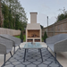 Ochre Living Perisher Complete Fireplace Kit installed in a backyard patio setting, framed by outdoor lounge seating and a coffee table for a symmetrical entertaining layout