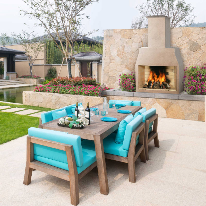 Ochre Living Perisher Complete Fireplace Kit integrated into an outdoor dining area beside a stone wall, adding warmth and ambience to a landscaped luxury backyard