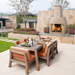 Ochre Living Perisher Complete Fireplace Kit beside an outdoor dining table with warm terracotta-toned seating, shown in a landscaped courtyard entertaining space.
