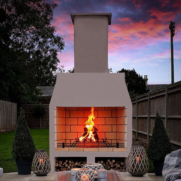 Ochre Living Perisher Complete Fireplace Kit with under log store, lit in a paved backyard at dusk