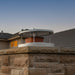Ochre Living Rain Cap chimney cap installed on a masonry chimney near a modern home, highlighting the durable metal construction and protective top cover