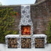Decoratively finished Ochre Living Ossa Complete Fireplace Kit in a courtyard garden, styled with a black-and-white patterned surface and stacked firewood for outdoor fireplace inspiration in Australia.