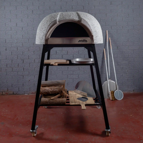 Front view of the Polito Antonius Garden Wood Fired Oven on a black steel stand with timber storage, pizza peels, and pizza tools displayed in an outdoor entertaining setting