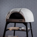 Angled side view of the Polito Antonius Garden Wood Fired Oven with open cooking chamber, textured dome exterior, timber pizza peels, and preparation tray on the oven stand