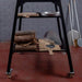 Front view of the Polito Antonius Tower Stand, black steel with a slatted lower shelf and four castors; props not included