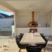 Polito Giotto in Copper built into a covered outdoor kitchen with a dining table