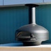 Polito Giotto wood fire oven in black on the BTS bench-top stand, on a white outdoor kitchen bench against a teal wall