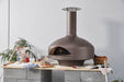 Polito Giotto wood fire oven in Bronze on a timber bench, fire lit