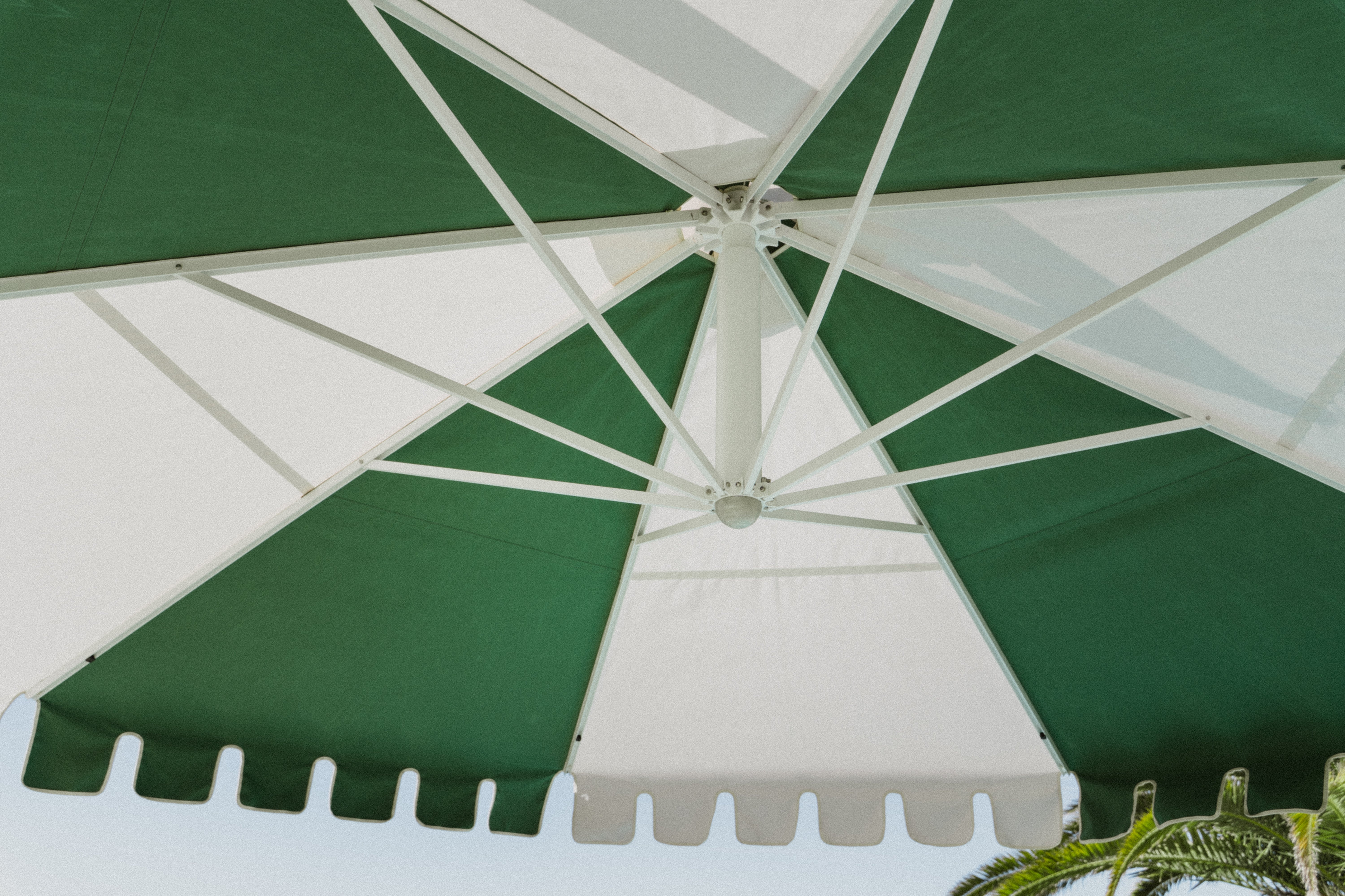 Revolvashade Designer Collection cantilever umbrella with a green and cream striped valance canopy, close view of the canopy and frame