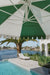 Revolvashade Designer Collection cantilever umbrella with a green and cream striped valance canopy shading an infinity pool courtyard