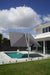 Revolvashade Signature Range cantilever umbrella with a charcoal canopy in the Square shape, tilted over a glass-fenced pool deck