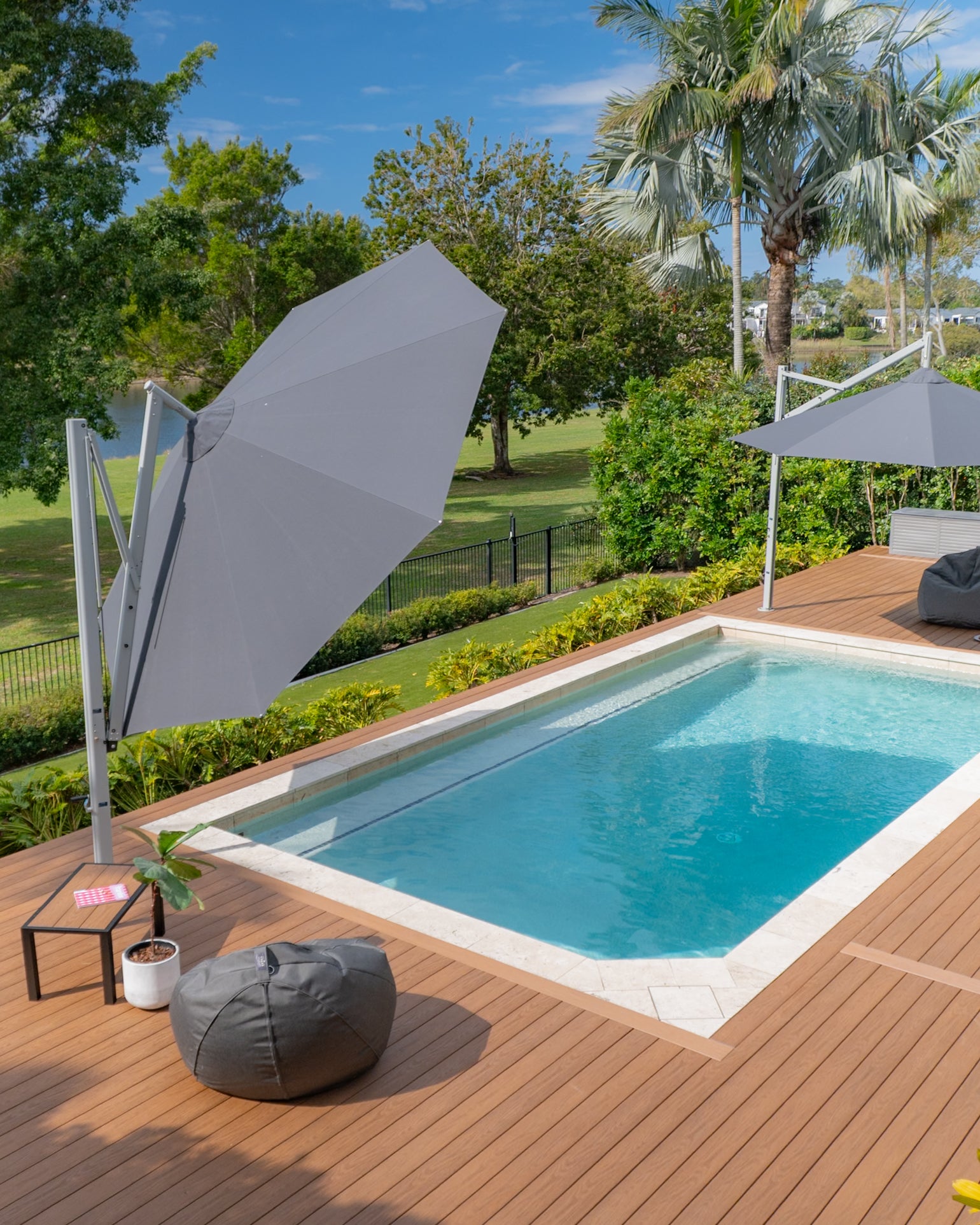 Revolvashade Signature Range cantilever umbrella with a charcoal canopy shading a riverside pool deck