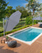 Revolvashade Signature Range cantilever umbrella with a charcoal canopy shading a riverside pool deck