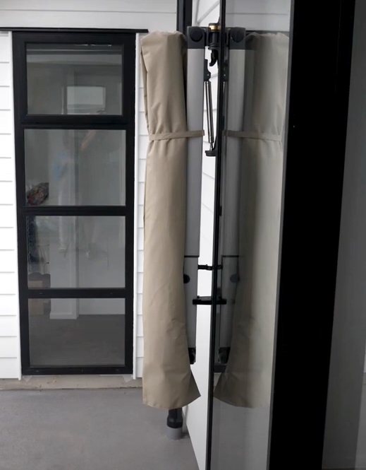 Shadowspec Retreat umbrella closed and stowed flat against a wall beside a door