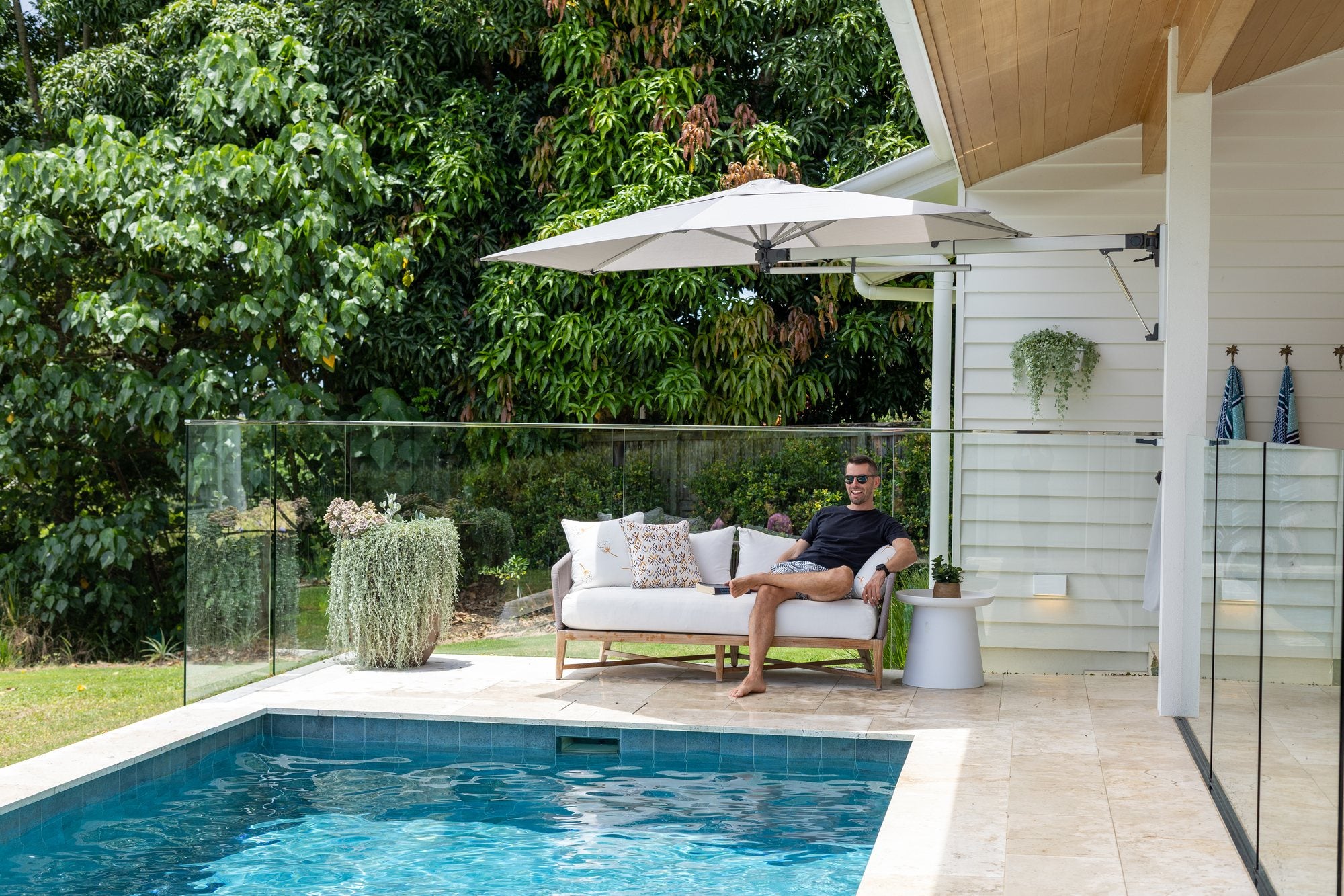 Shadowspec Retreat wall-mounted umbrella shading a poolside lounge setting