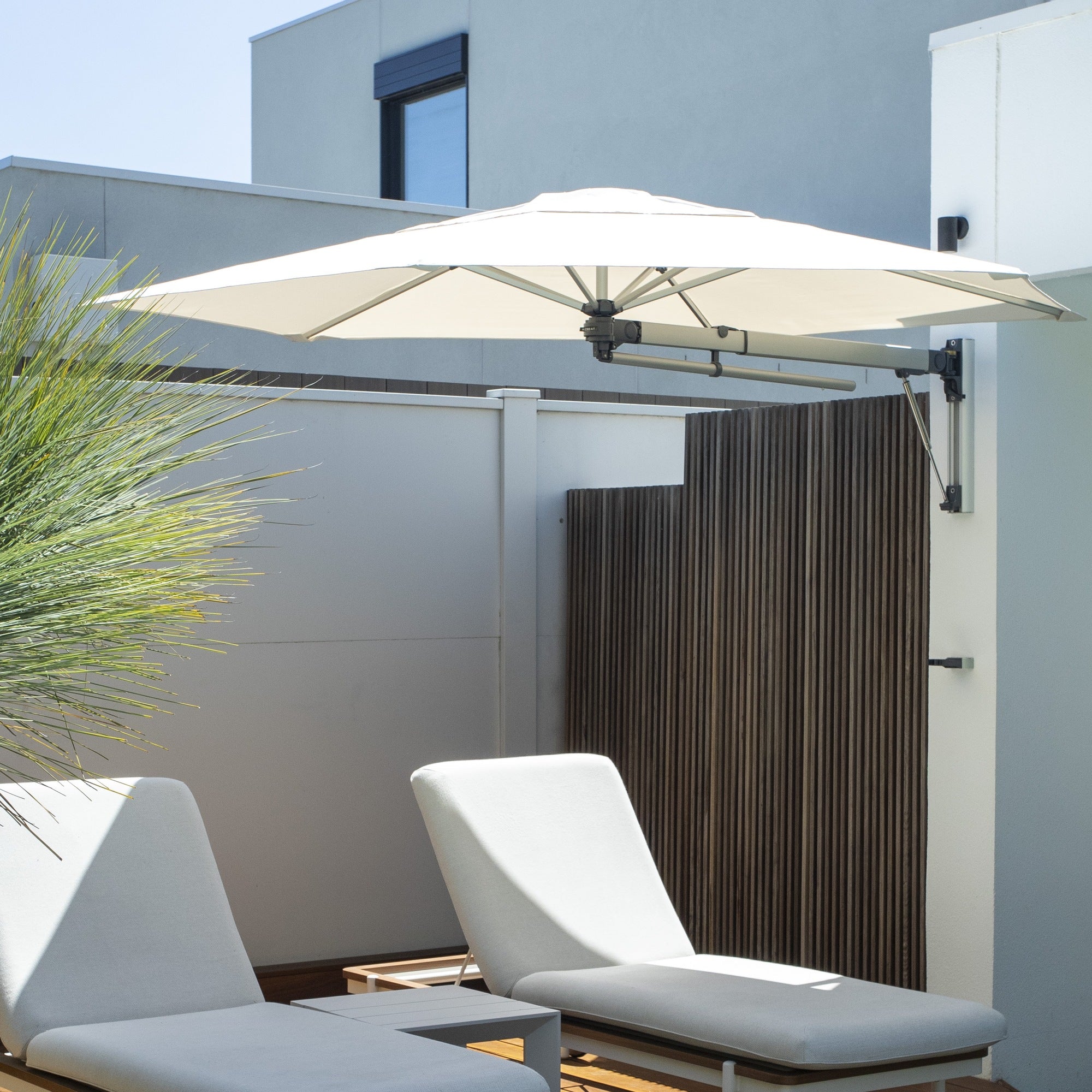 Shadowspec Retreat wall-mounted umbrella with an Oyster canopy over poolside loungers