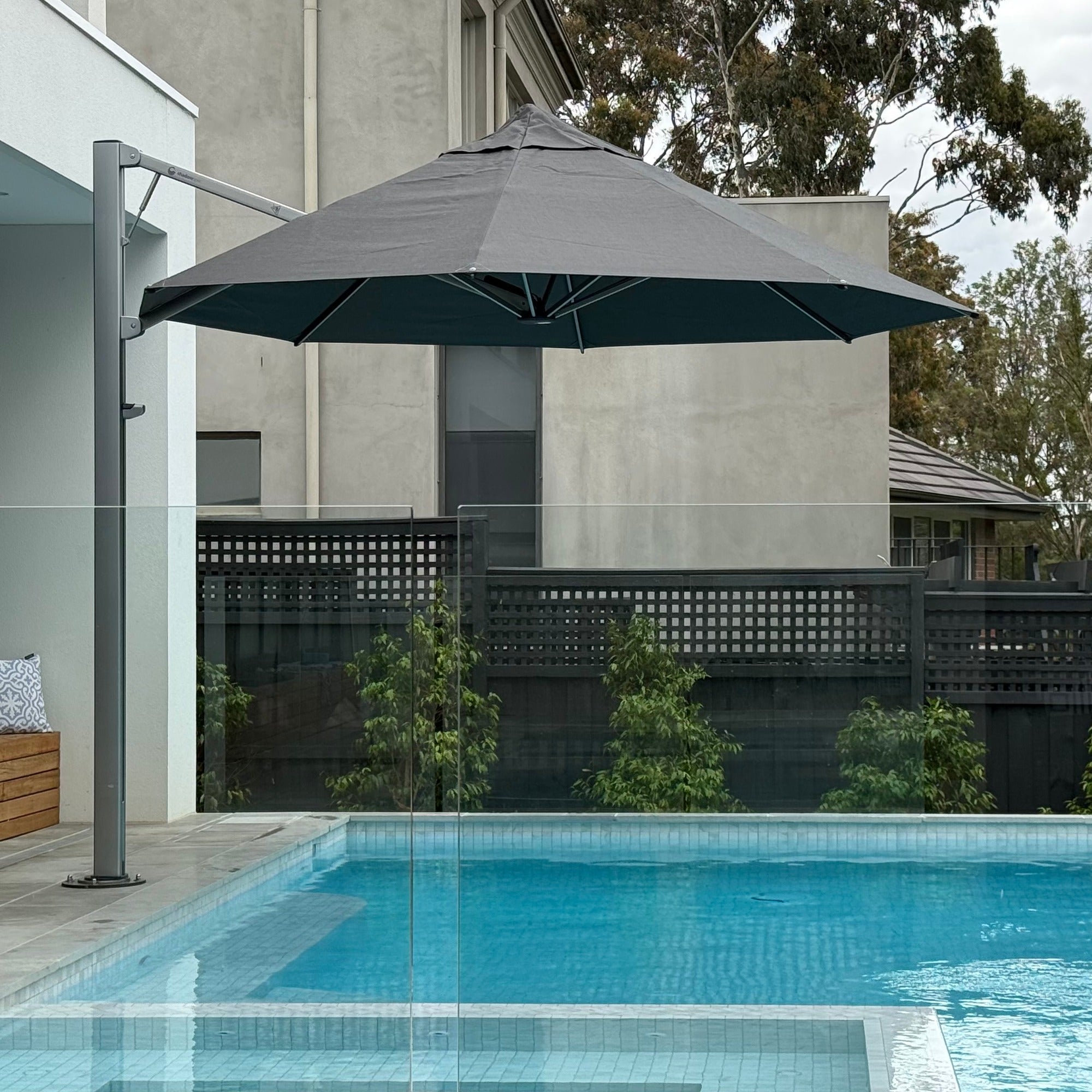 Shadowspec Serenity cantilever umbrella, 3.5m octagon Black canopy on a Space Grey frame, beside a pool