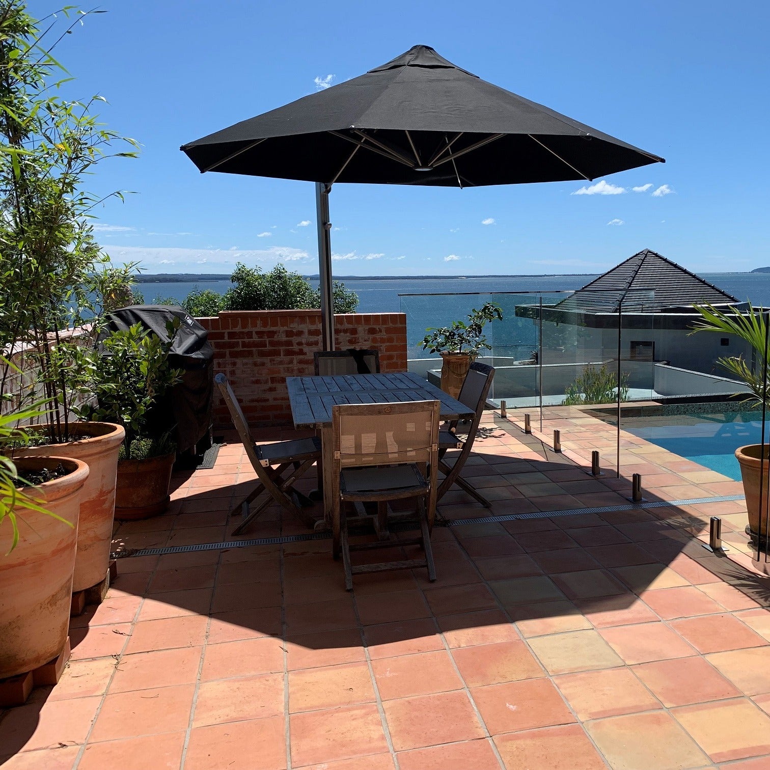 Shadowspec Serenity cantilever umbrella, octagon Black canopy on a Space Grey frame, over a terrace dining setting