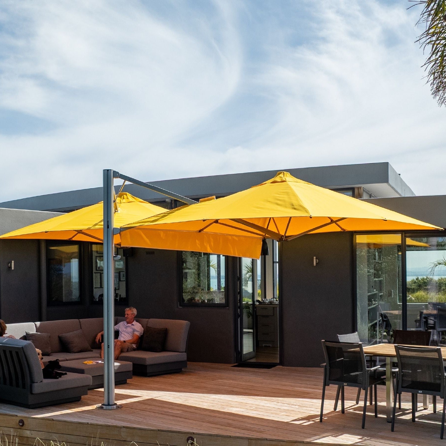 Shadowspec Unity twin-canopy cantilever umbrella in yellow over an outdoor lounge