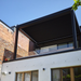 Exterior view of a black SkyFlex Delta motorised aluminium louvred pergola installed on an upper-level terrace