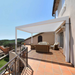White SkyFlex Delta motorised aluminium louvred pergola installed on a sunny balcony terrace with outdoor seating