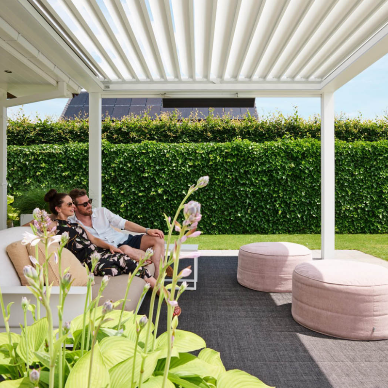 View from beneath a white SkyFlex Delta motorised aluminium louvred pergola covering a garden seating area