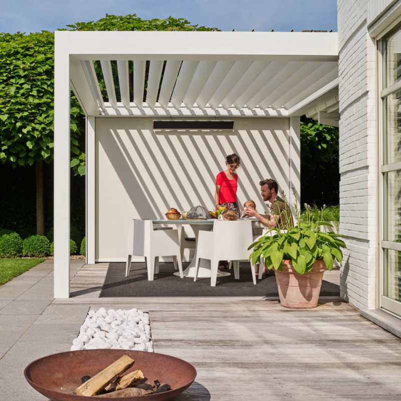 White SkyFlex Delta motorised aluminium louvred pergola over a family outdoor dining area beside a house