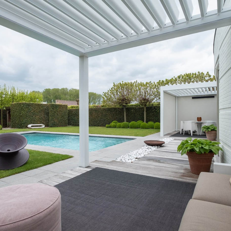 View from under a white SkyFlex Delta motorised aluminium louvred pergola overlooking a swimming pool and garden