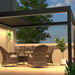 Black SkyFlex Delta Open Sky motorised aluminium louvred pergola on a balcony terrace at dusk, with integrated LED lighting above wicker dining chairs