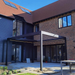 Black SkyFlex Delta Open Sky motorised aluminium louvred pergola installed in a residential courtyard behind a brick house extension