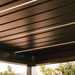 Close-up of black pergola louvres with integrated warm LED strip lighting inside a SkyFlex Delta Open Sky motorised aluminium pergola