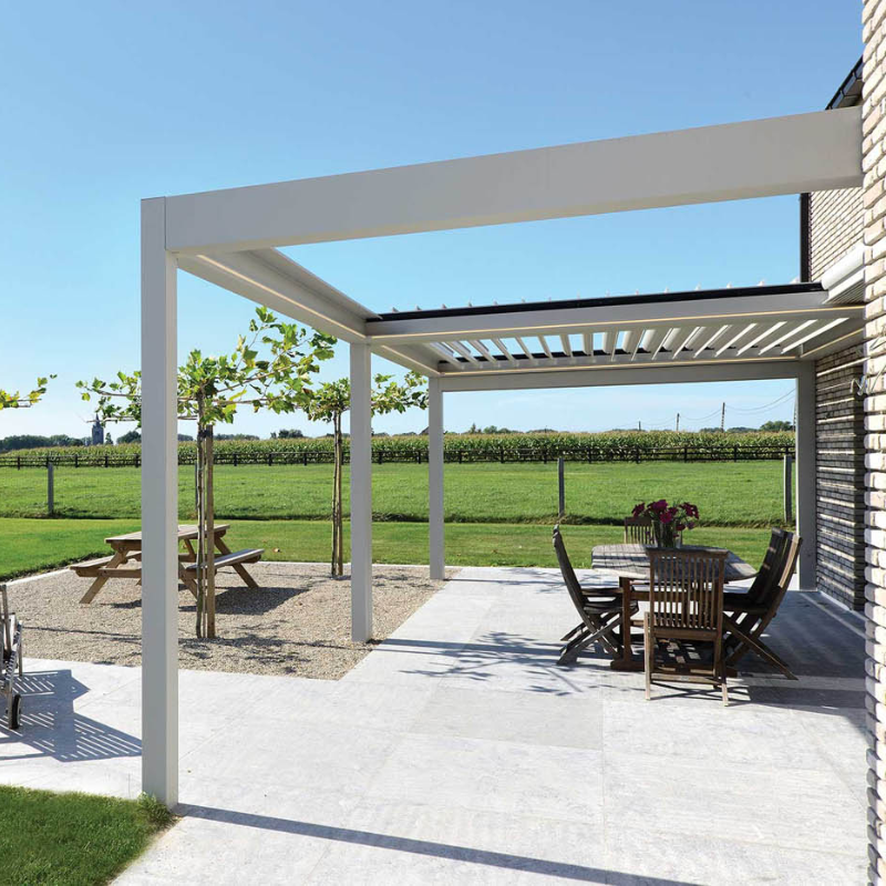White SkyFlex Delta Open Sky motorised aluminium louvred pergola covering a countryside patio dining area beside a house in daylight