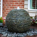 Medium Stacked Slate Sphere fountain installed among garden plants