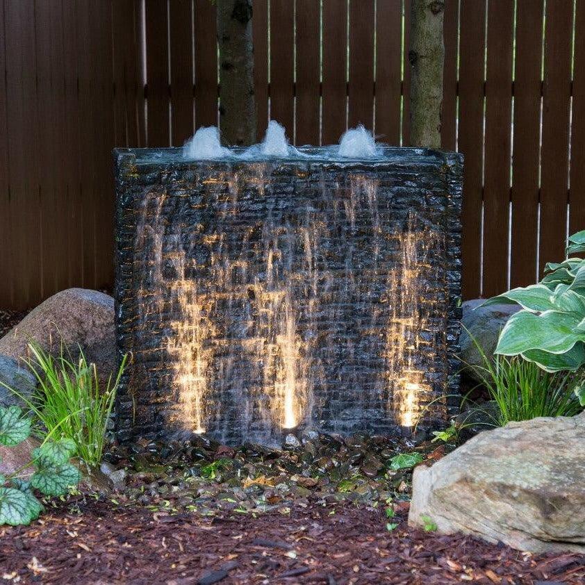 Curved Stacked Slate Spillway Wall fountain at night, lit with spotlights sold separately