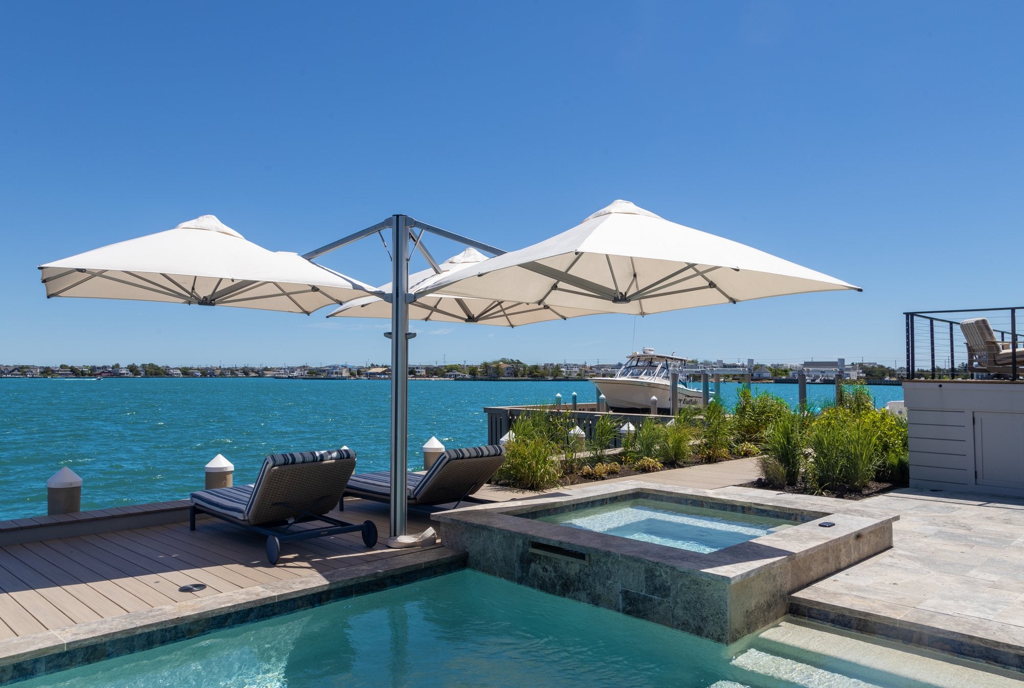 Shadowspec Unity trio umbrella over a waterside pool deck