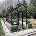 Winter Gardenz Elite 8ft x 10ft glasshouse with black aluminium frame on a schist stone base wall in a garden