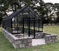Winter Gardenz Elite 10ft wide glasshouse on a stone base wall with a paved entry, shown with a shade cover fitted